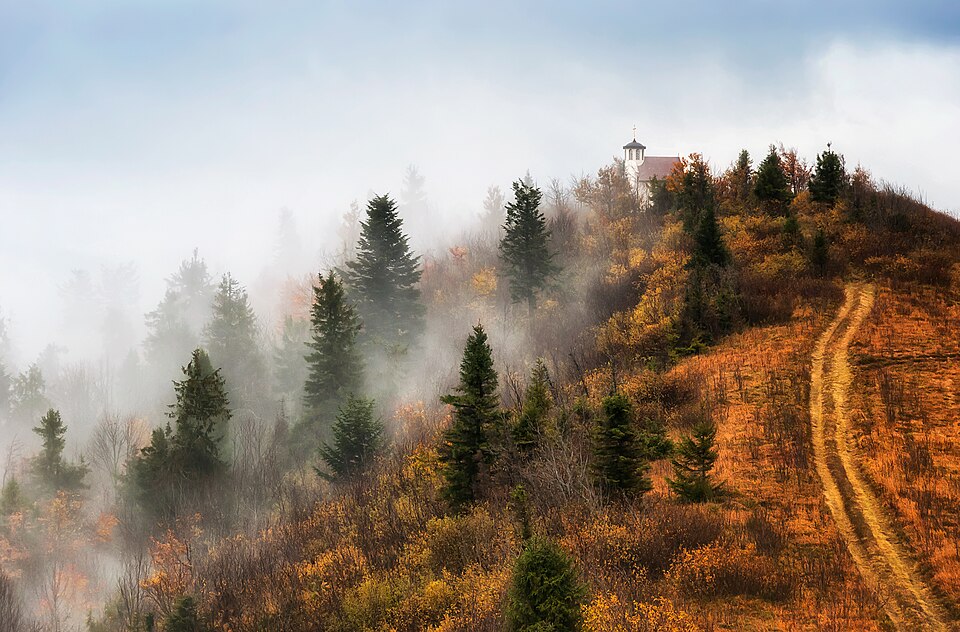 Morning fogs in the Skolivskyi Beskids. At the top there is a church, the highest in Ukraine, Skolovsky city council, Ukraine.
