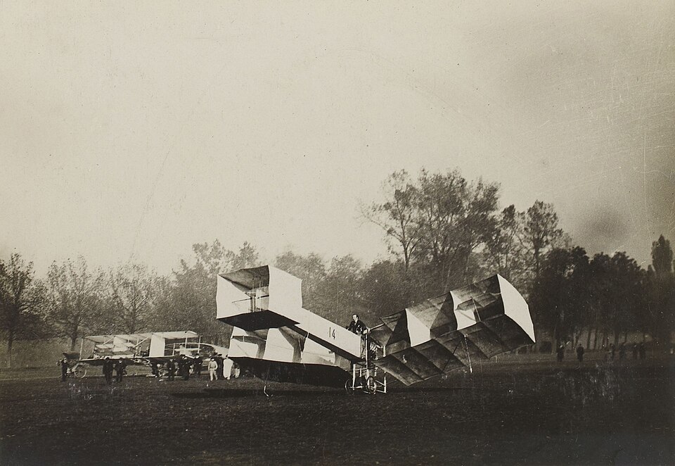(Français) Le 14-bis de Alberto Santos Dumont avec, en arrière-plan, le Blériot IV. [Collection Jules Beau. Photographie sportive] : T. 33. Années 1906 et…