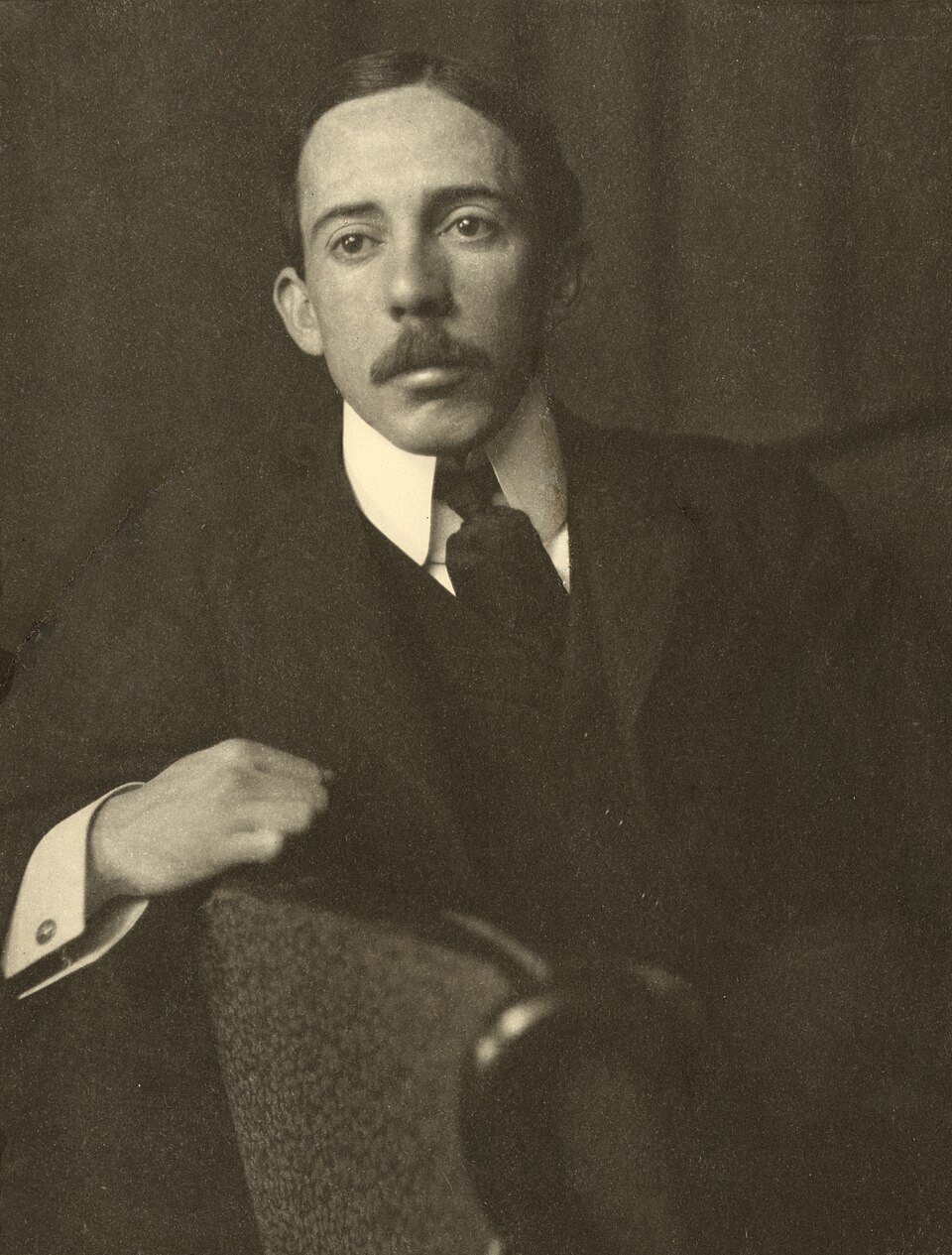 Alberto Santos-Dumont, half-length portrait, facing front, sitting, with right arm resting on back of chair.