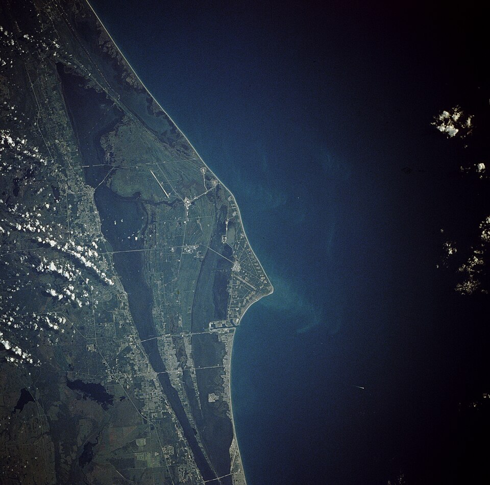 Cape Canaveral, Florida and the NASA John F. Kennedy Space Center are shown in this near-vertical photograph. Numerous launch pads line the Atlantic Ocean…