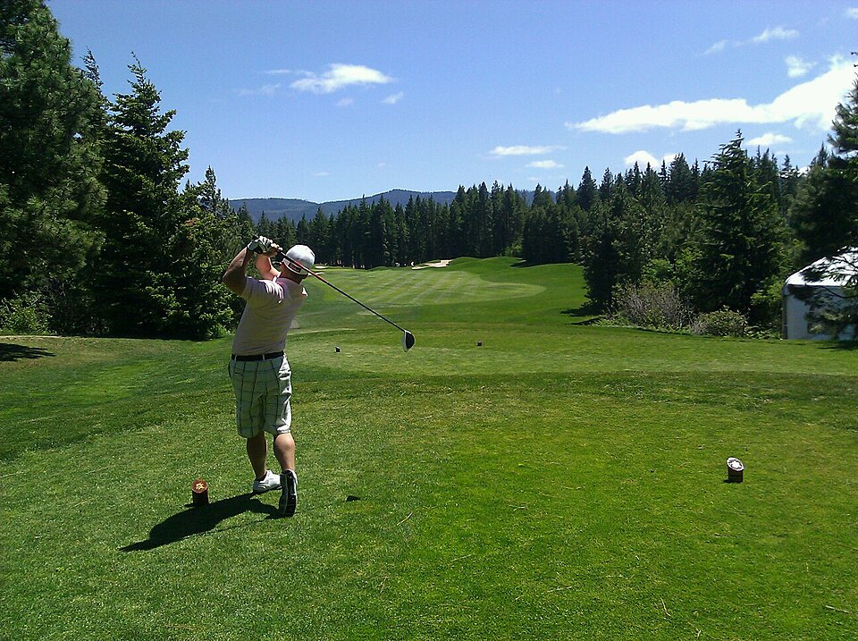 A golfer taking a tee shot to begin a round of golf.