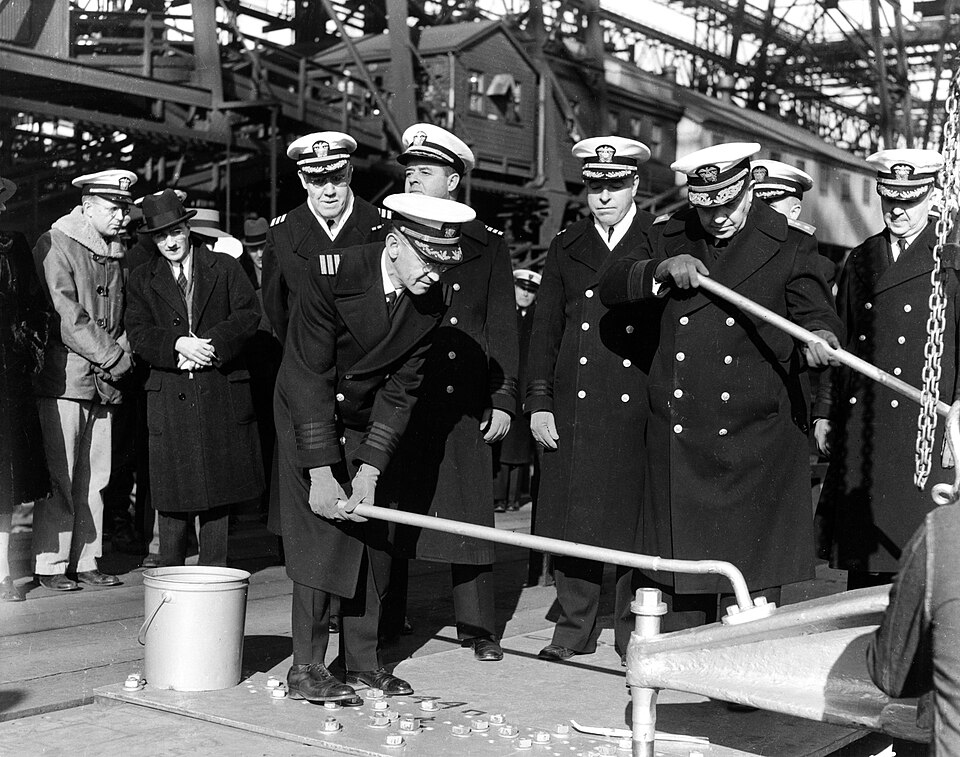 Driving first rivet during USS Missouri's keel laying, 6 January 1941. Rear Admiral Clark H. Woodward, Commandant of the Navy Yard, (second from right) did…