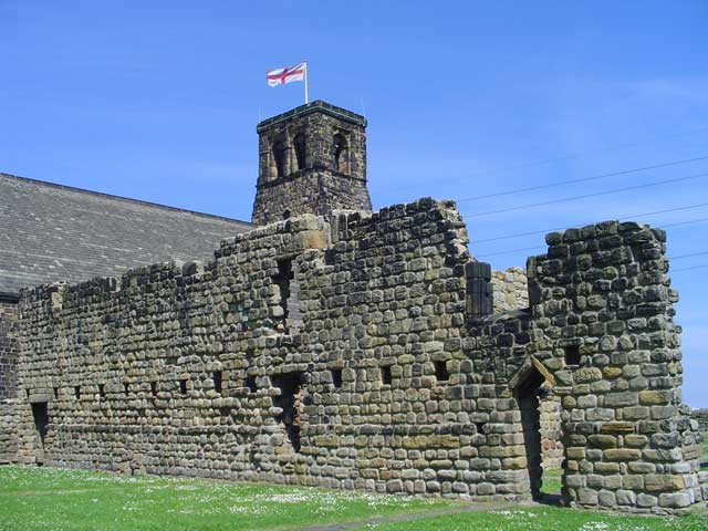 Surviving wall of the west range of St Paul's Monastery, Jarrow, Tyne and Wear, seen from the southwest. In the background is the Norman tower of St Paul's…