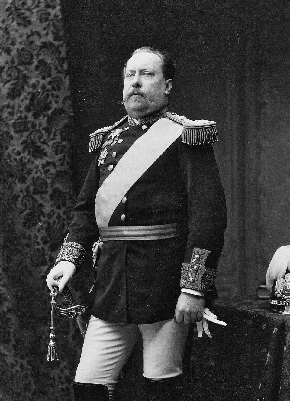 Portrait of Louis I, King of Portugal, standing full-length, facing right, in full dress uniform. The king holds a saber in his left hand and a white glove…