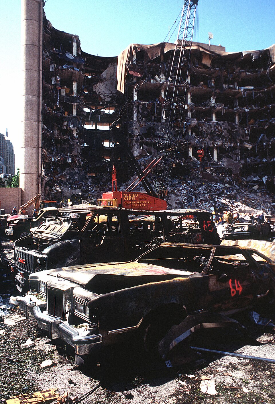 The bombed remains of automobiles with the bombed Federal Building in the background. The military is providing around the clock support since a car bomb…