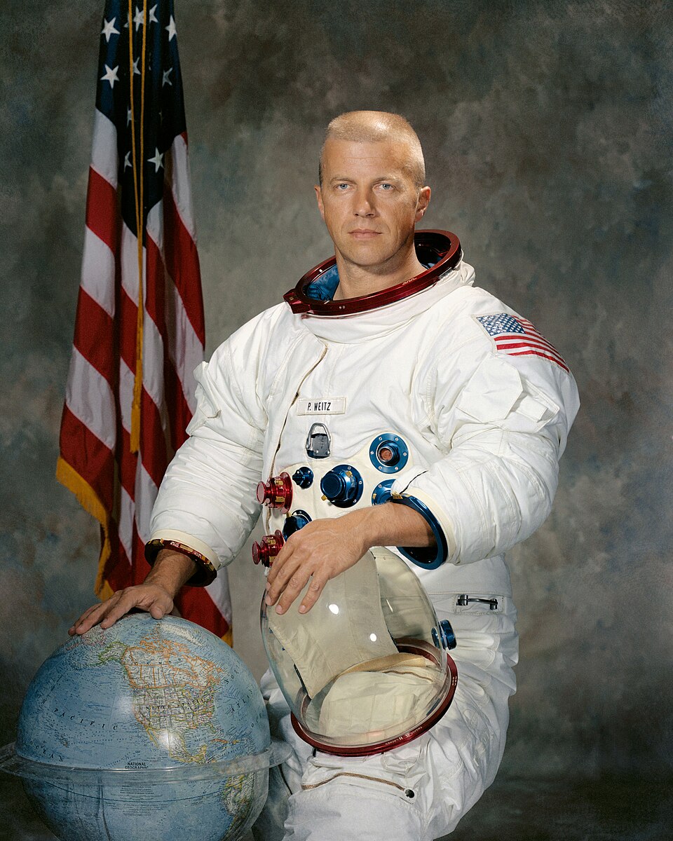 Portrait of Astronaut Paul J. Weitz, in spacesuit and holding helmet.
