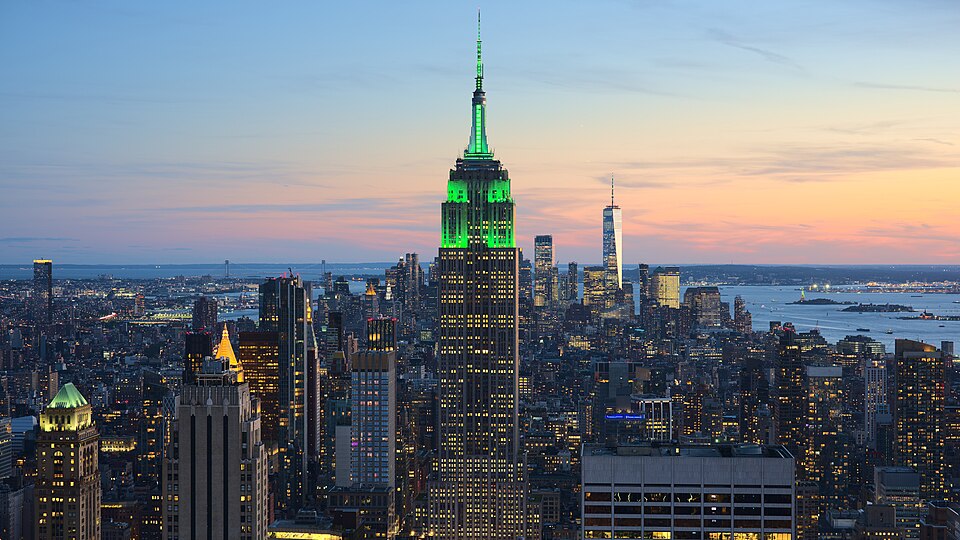 View of the Empire State Building in New York City from the Top of the Rock at 30 Rockefeller Plaza during sunset. The tower was illuminated in green in…